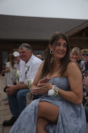 Wedding party members in blue dresses react emotionally during outdoor celebration.