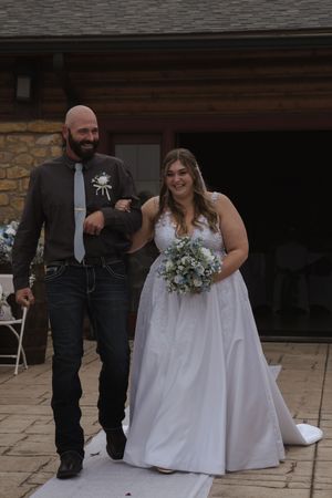 Wedding couple poses together on stone patio during their outdoor ceremony.