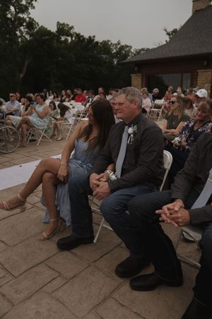 Wedding attendees sitting on chairs during an outdoor evening ceremony.