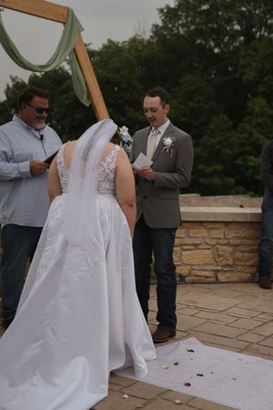 White wedding dress train flowing on stone patio during outdoor ceremony.