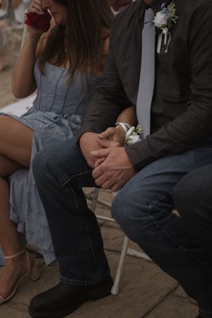 Close-up of formal attire and corsages at outdoor wedding ceremony.