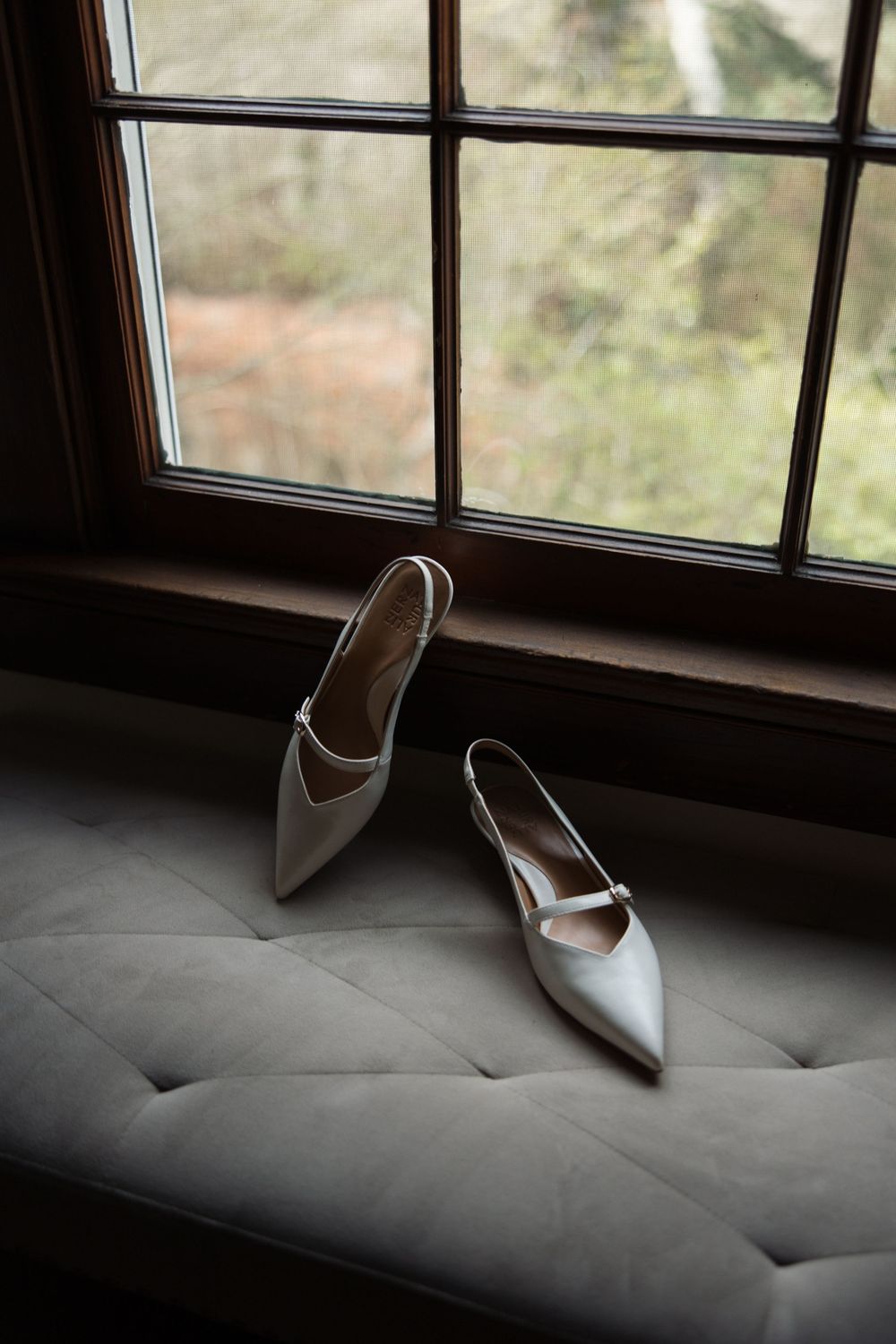 Bride’s wedding shoes displayed on a windowsill with natural light