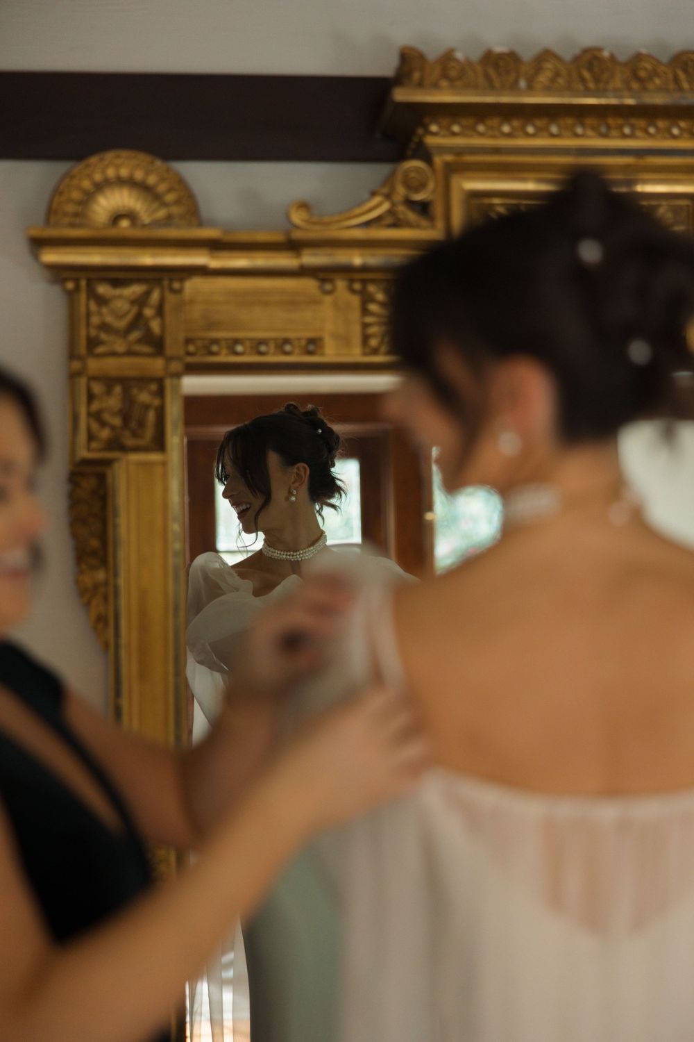 Getting ready moment with bride’s sister-in-law helping with her dress