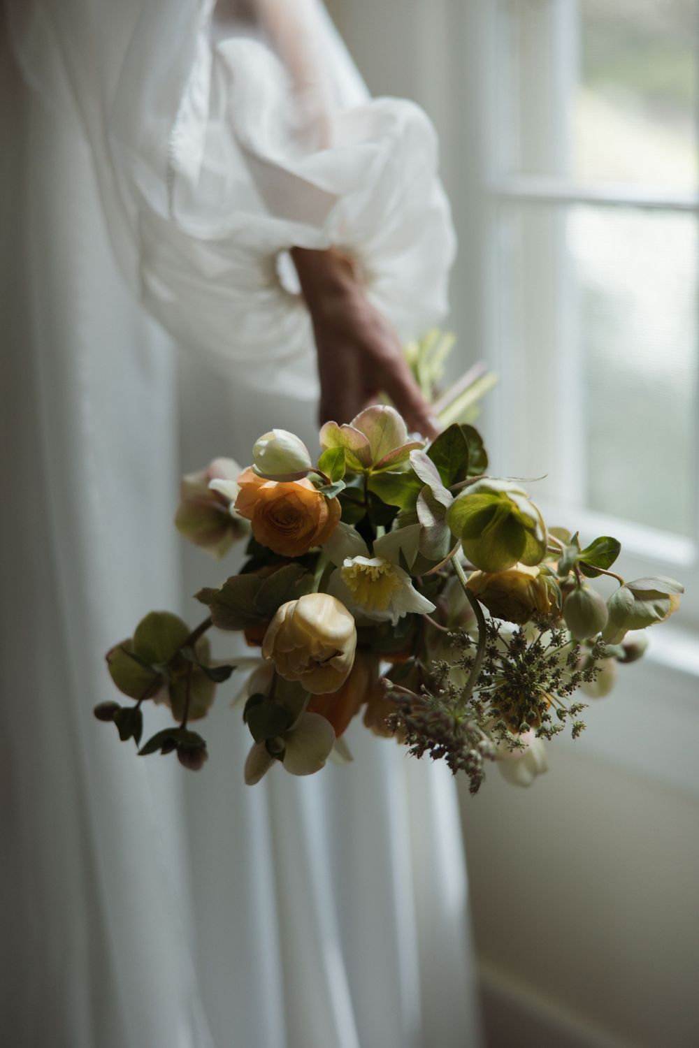 Wedding bouquet and sleeve detail photographed by a window with soft natural light