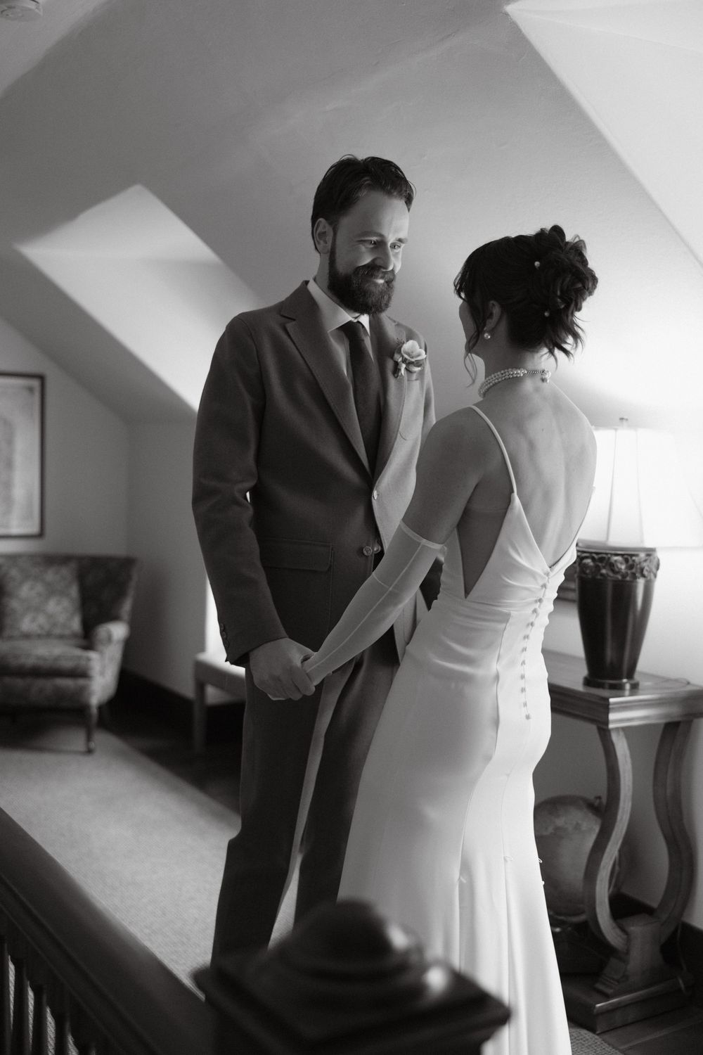 Black and white first look photo of bride and groom holding hands and smiling