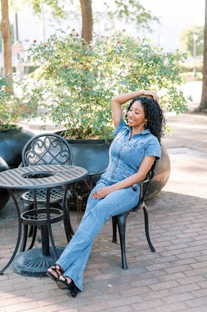 Four sequential shots of someone relaxing and laughing on a black metal patio bench in a denim jumpsuit outdoors.