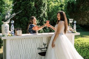 People enjoying an outdoor garden party with white tables and decorations in a lush green setting.