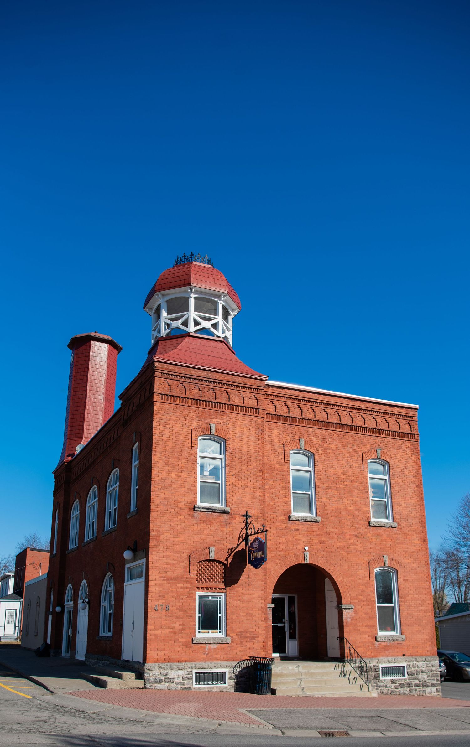 Historic red brick building with white trim and decorative cupola tower against bright blue sky in New England town.