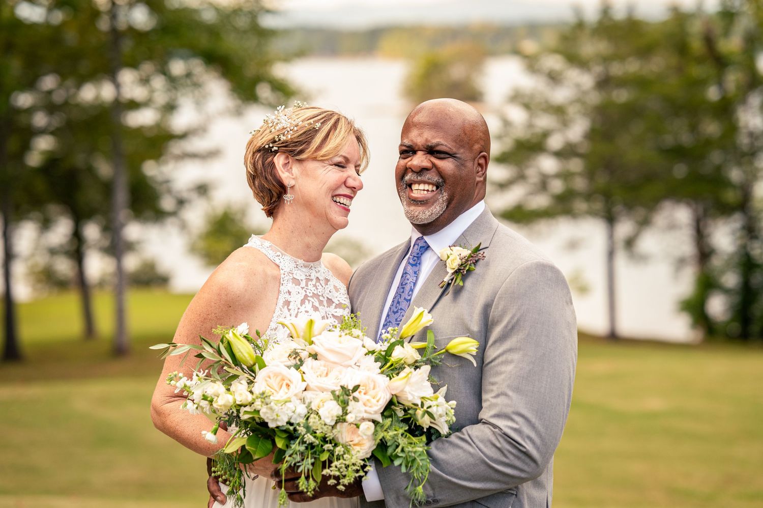 Happy couple shares intimate moment during outdoor wedding ceremony with beautiful bouquet of white roses and lilies.