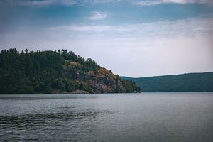 A panoramic series of lake views showing forested hills and tranquil waters under an overcast sky.