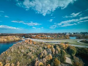 Aerial view of a river bend surrounded by autumn foliage and urban development.
