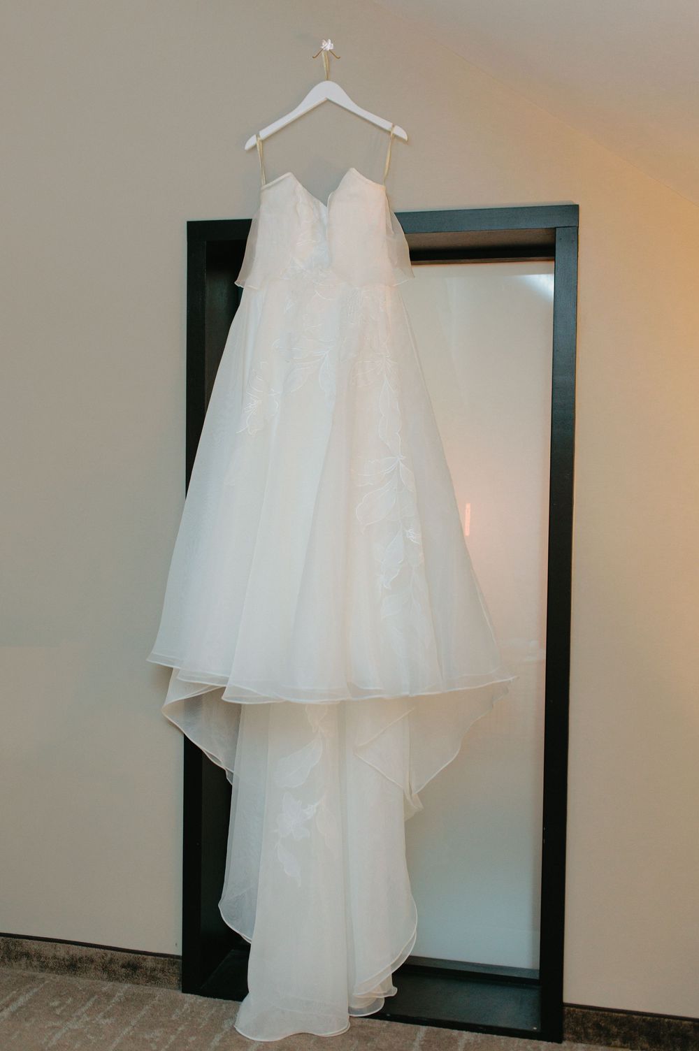 Three white wedding dresses on display show different angles of a flowing, elegant gown with a full skirt and train.