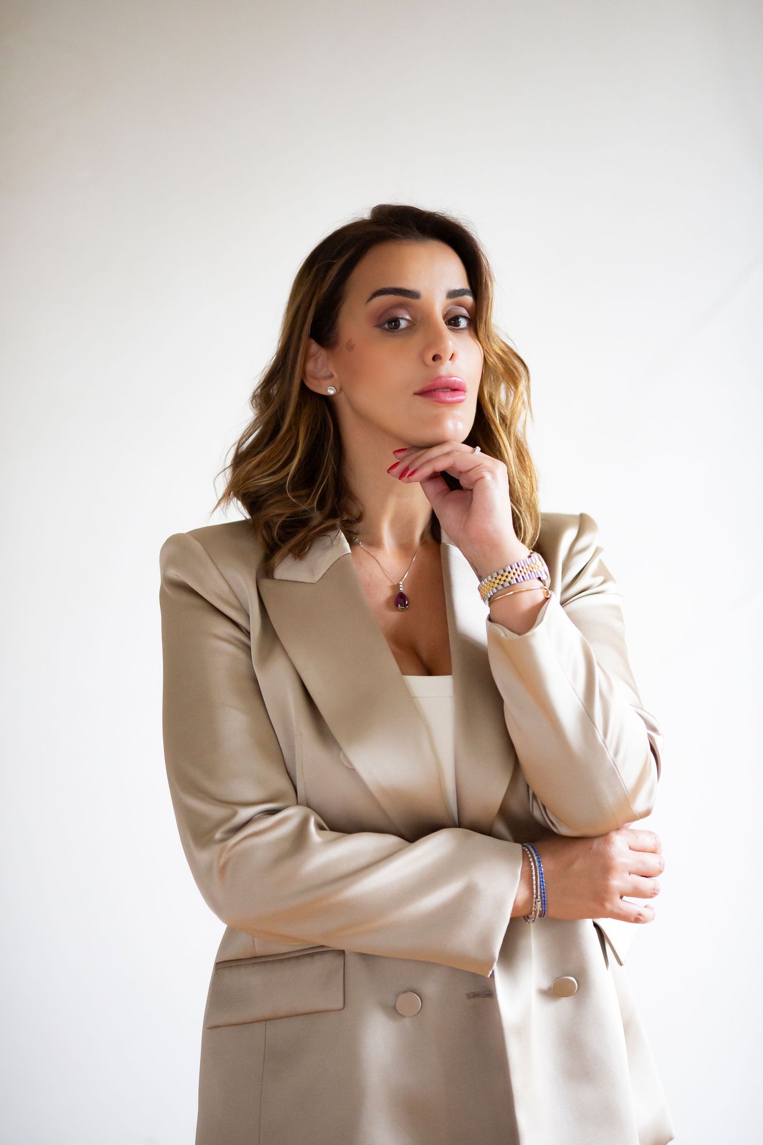 Professional wearing a sleek white pantsuit stands confidently in a minimalist interior space.