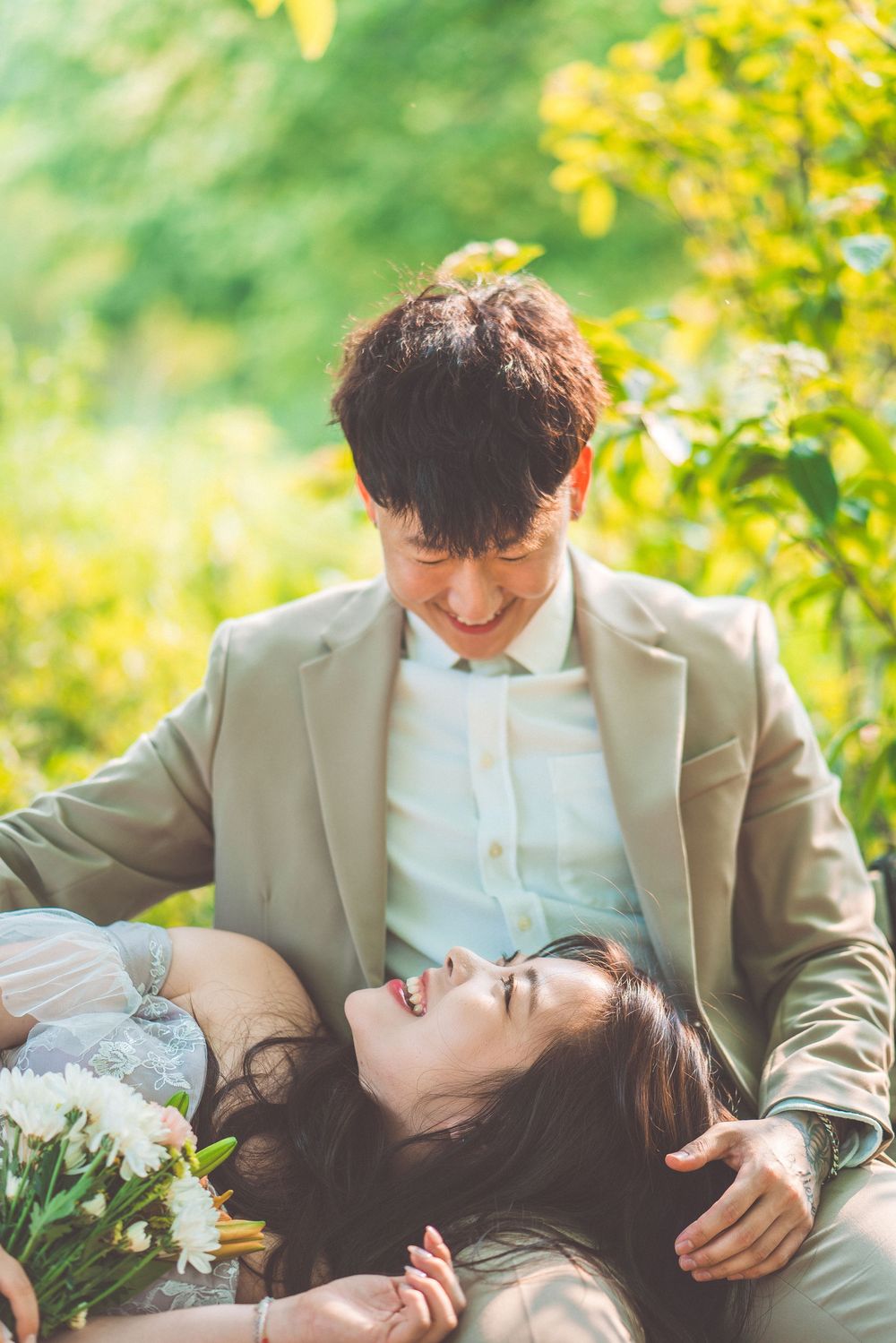 Couple laying in grass sharing joyful moment with flowers.