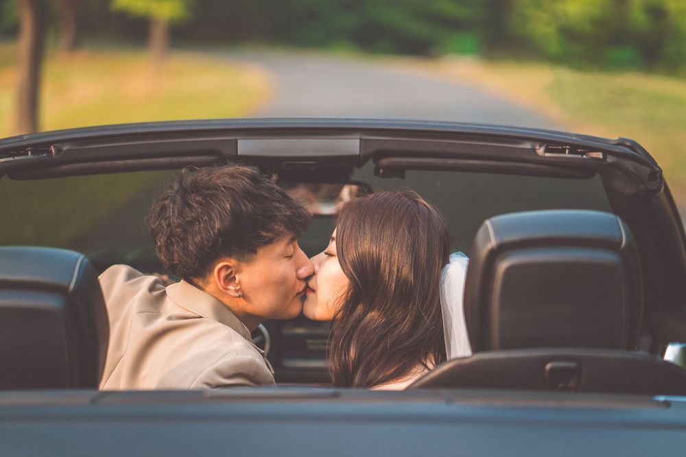 Romantic couple sharing kiss in convertible car.