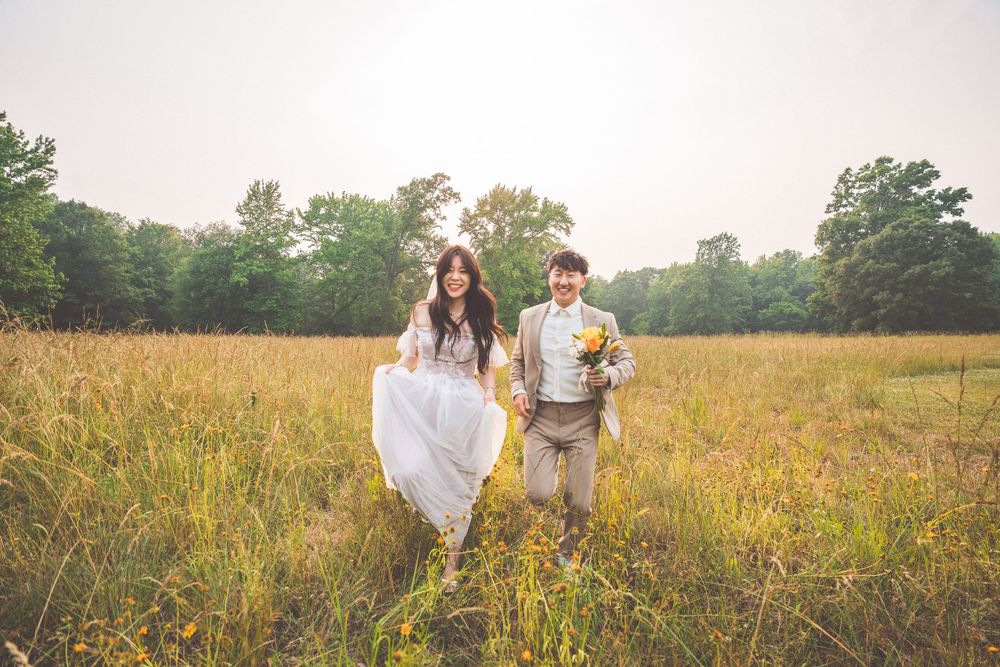 Couple walking through golden field during sunset photo shoot.