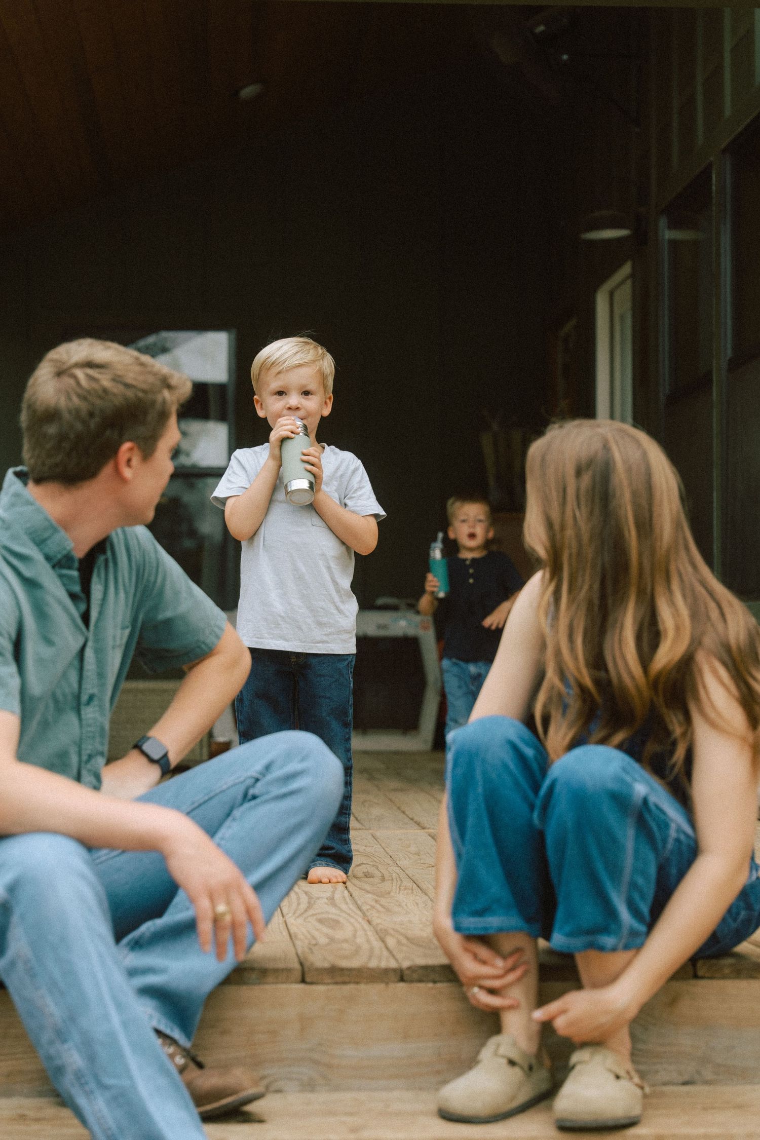 A family sits together on a wooden porch while enjoying drinks on a relaxed afternoon.