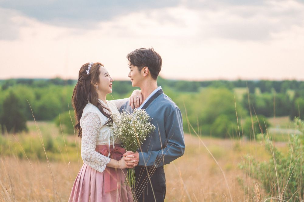 Couple sharing romantic moment in field with wildflowers and soft natural lighting.