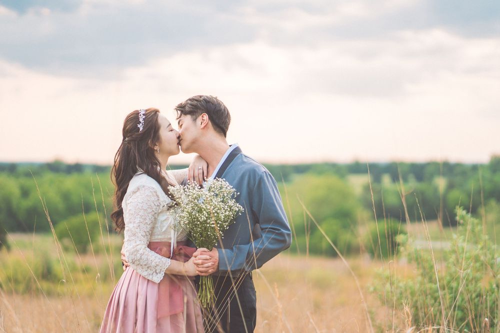 Romantic embrace in golden field with bouquet of baby's breath flowers.