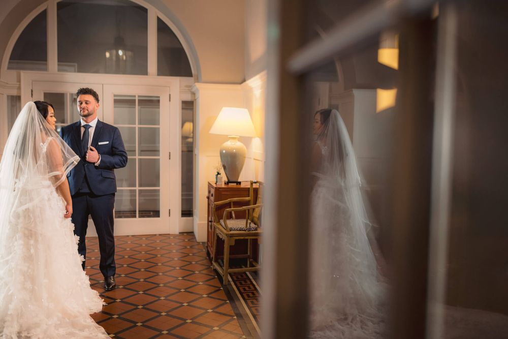 Romantic wedding moment captured through doorway in elegant indoor venue with arched details.