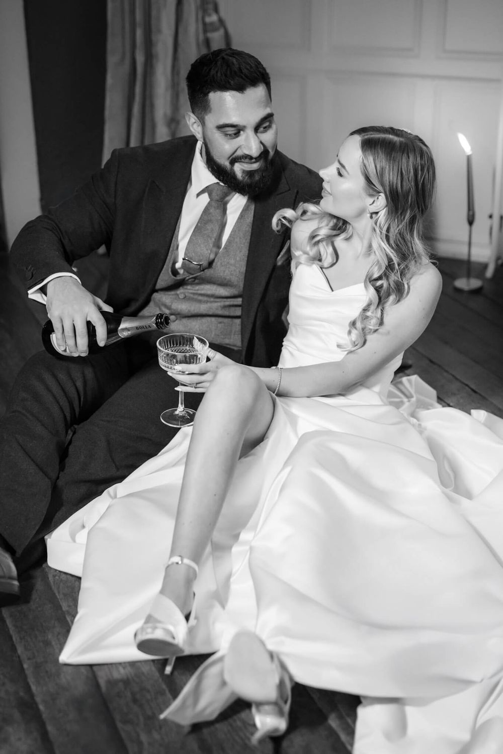 Intimate black and white portrait of a wedding couple sharing champagne and laughter.