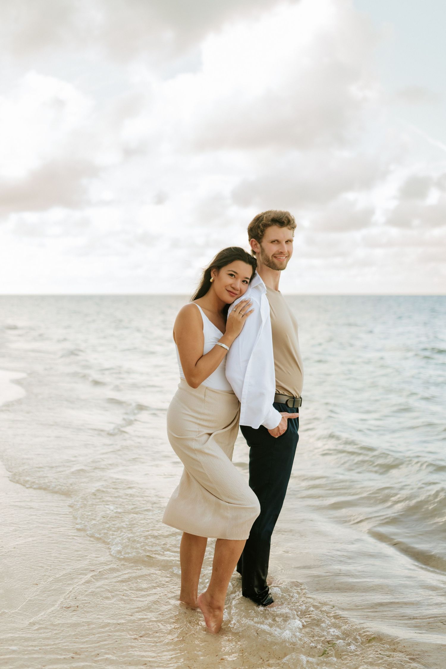 A romantic beach portrait of a couple enjoying the ocean waves at sunset.