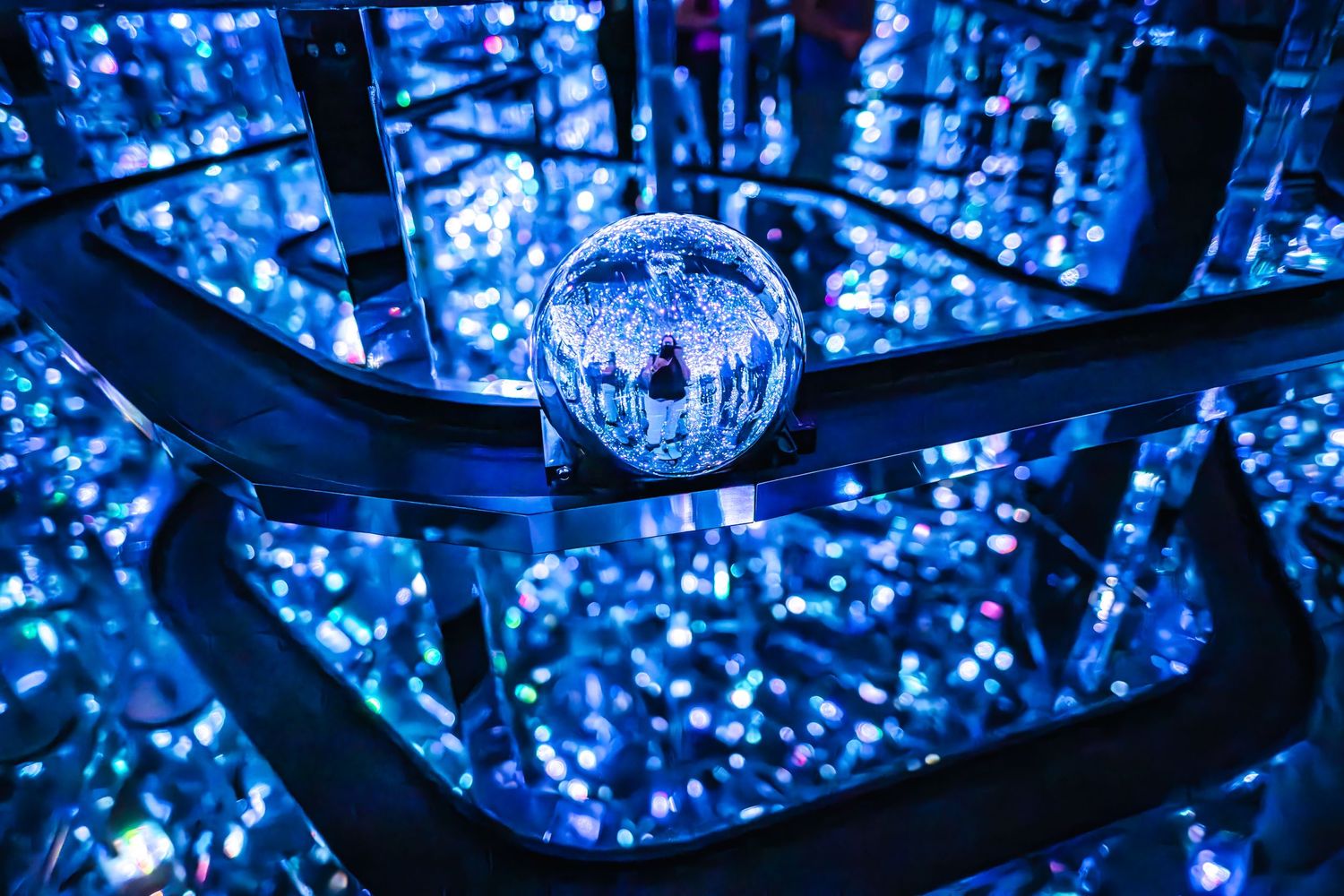 A disco ball reflects vibrant blue light in a dark nightclub setting creating a mesmerizing atmosphere.