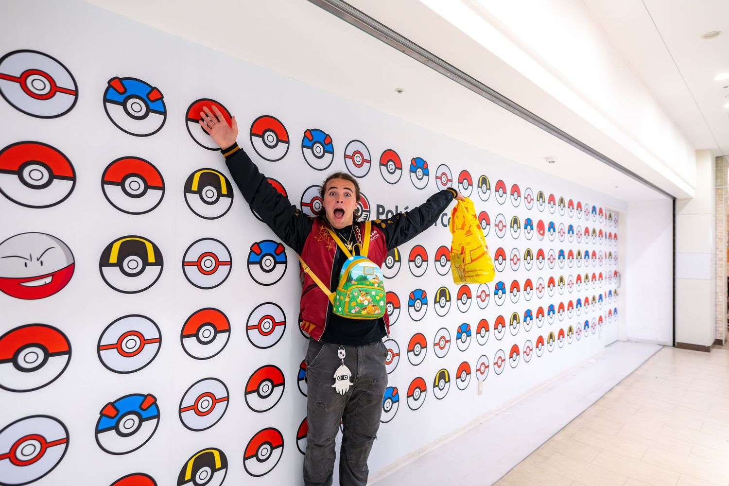 A lively scene against a wall decorated with colorful Pokemon pokeball patterns and designs.
