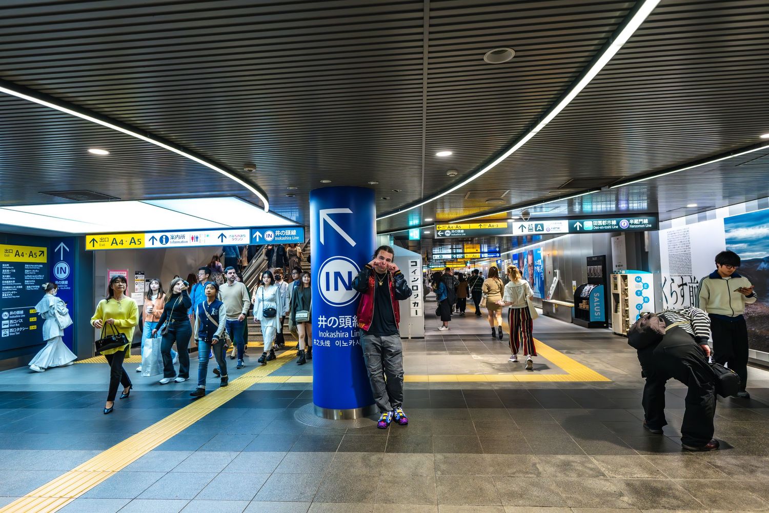 Busy underground shopping mall corridor in Tokyo with bright signage and commuters walking through the passage.
