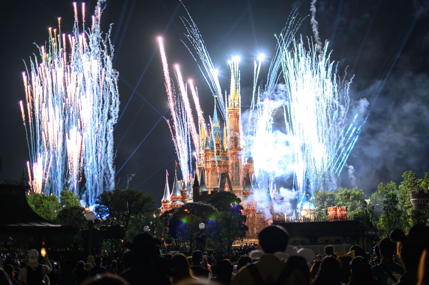 Spectacular fireworks display illuminates Cinderella Castle at Disney World with colorful pyrotechnics against night sky.