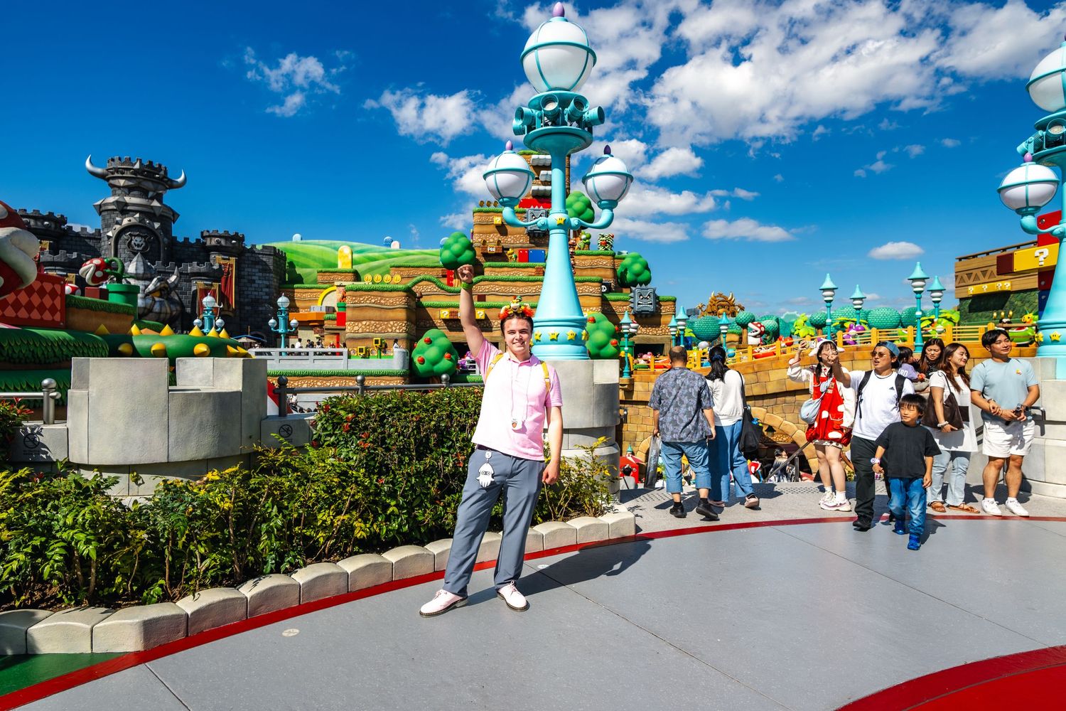 Theme park guests enjoy a sunny day in Super Nintendo World with colorful toadstools and scenery at Universal Studios.