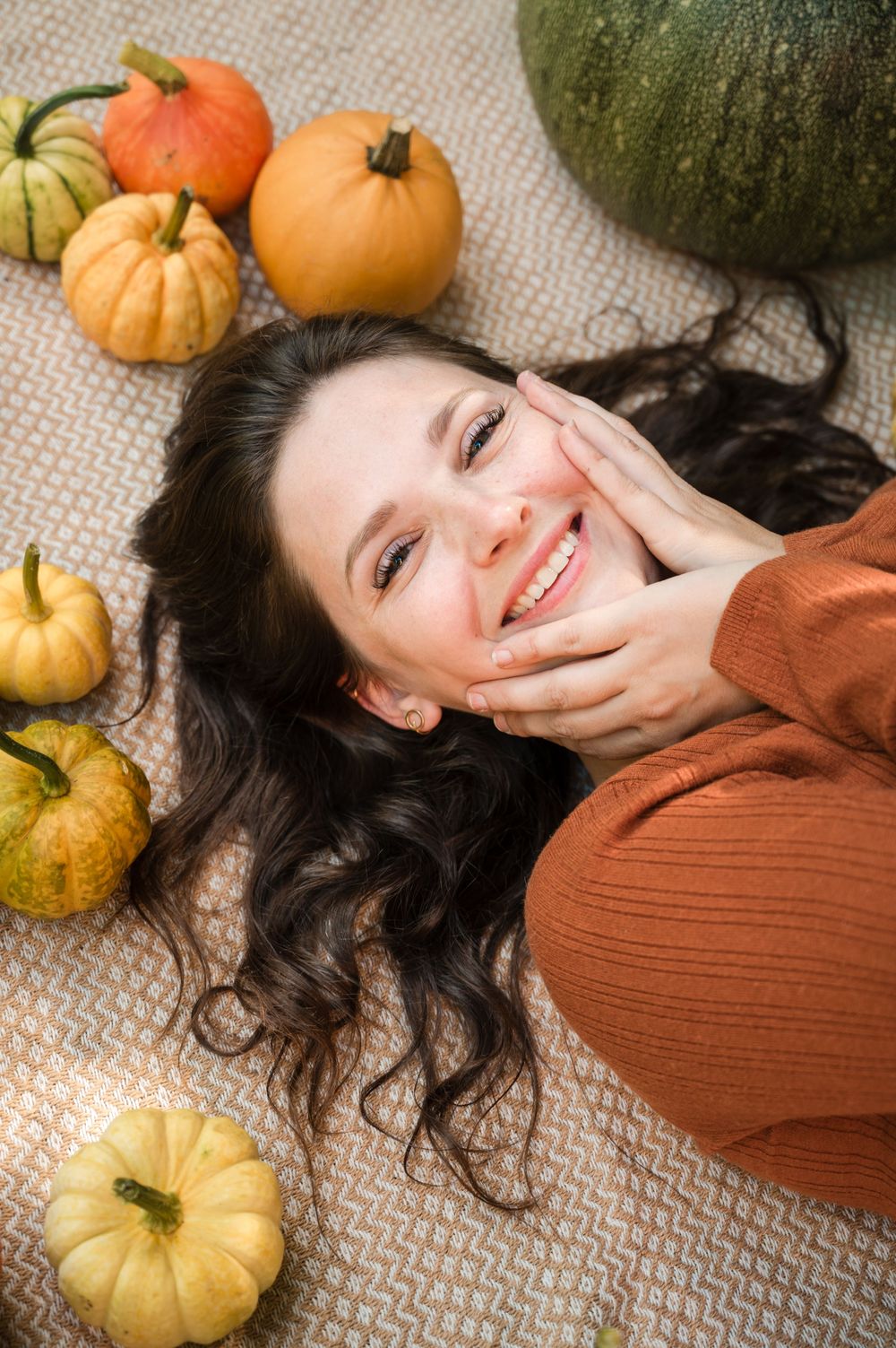 À Huy, portrait d’une femme allongée entourée de potirons lors d’une séance photo en automne
