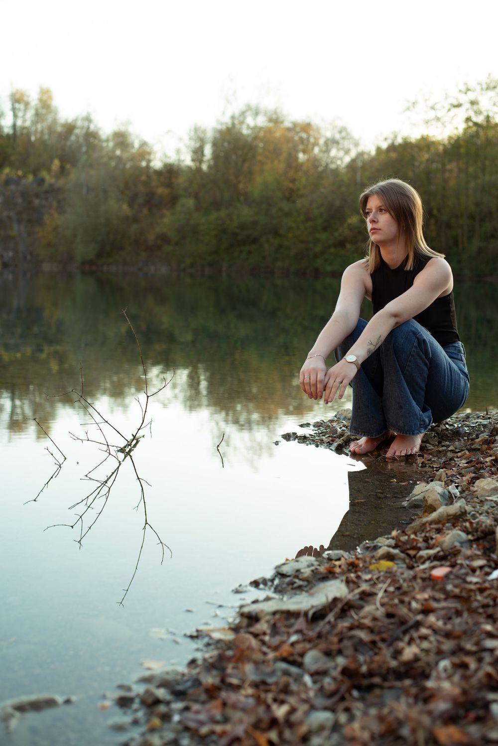 À Charleroi, portrait d’une femme assise au bord du lac d’une ancienne carrière regardant au loin lors d’une séance photo