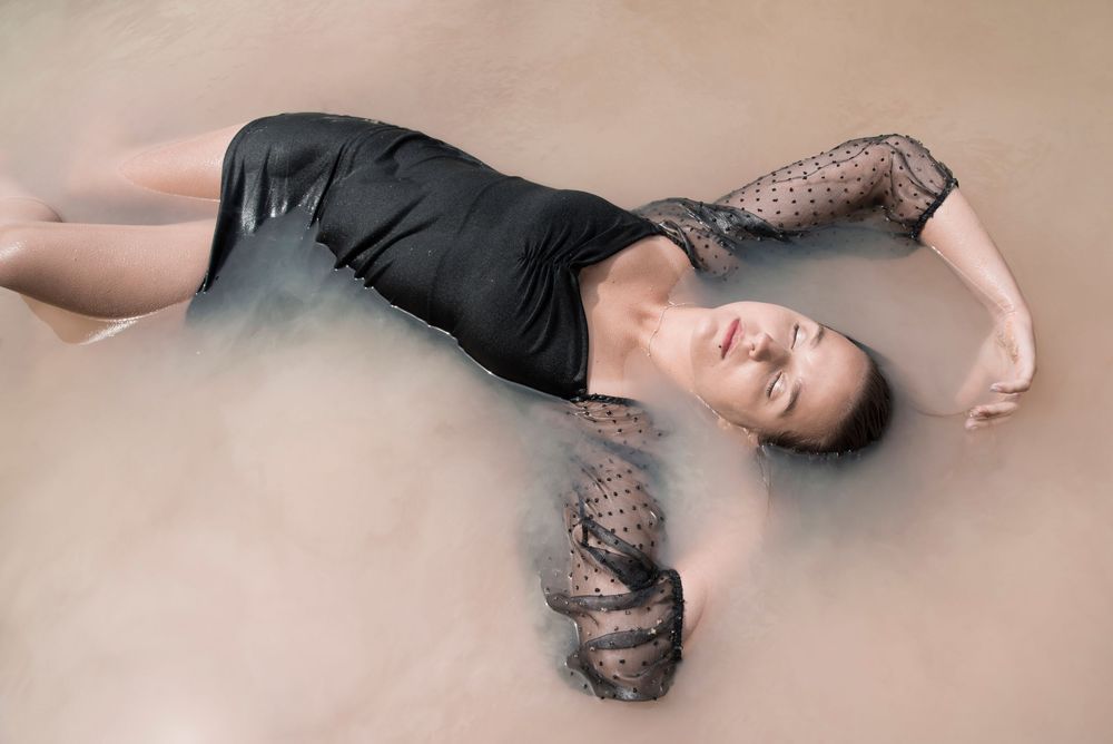 À Ohey, portrait individuel d’une femme allongée dans un lac lors d’une séance photo en pleine nature