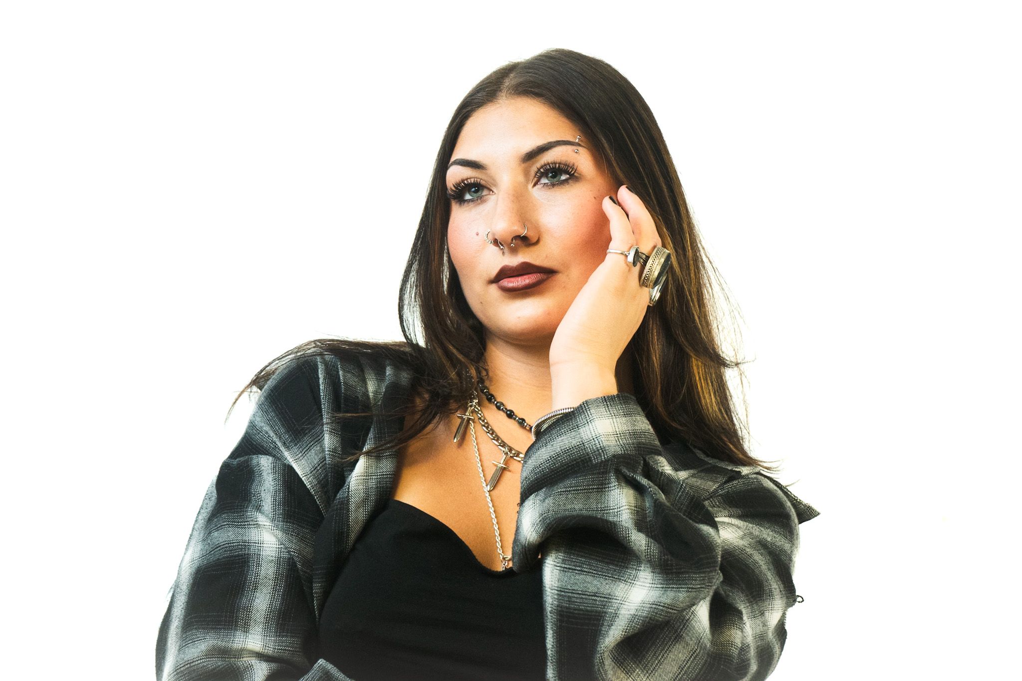 Person wearing a plaid flannel jacket and black top poses against white background.