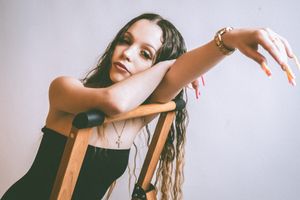 Artistic portrait of model posing with chair in studio setting.