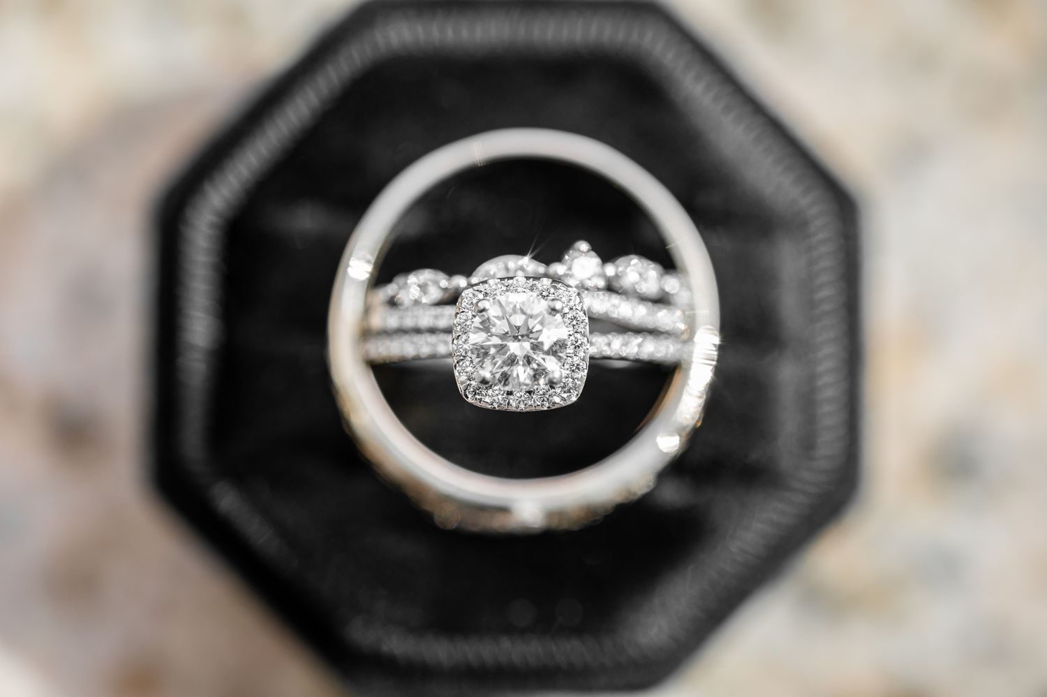 Diamond halo engagement ring with wedding band set displayed in black octagonal ring box.