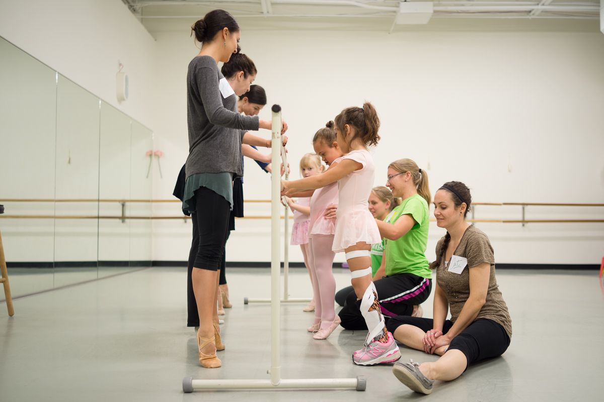 Dance students receive instruction during a ballet class in a bright studio.