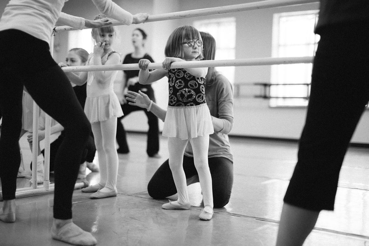 Young dancers practicing ballet positions in a mirrored studio.