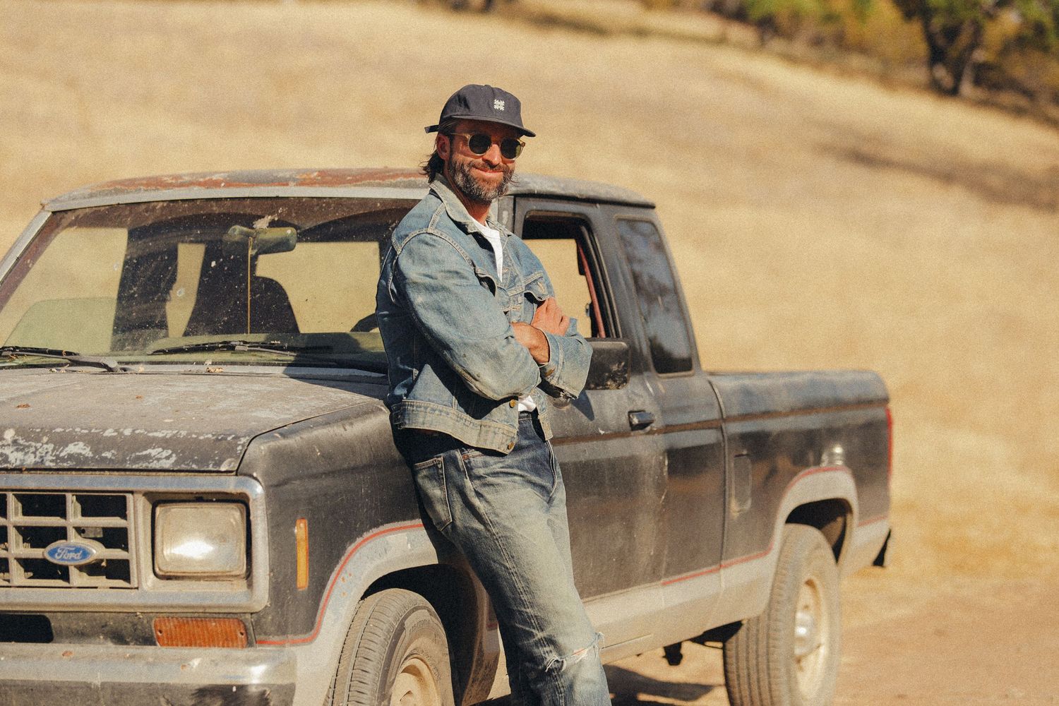 A series of vintage pickup trucks parked in a row on a dusty rural landscape.