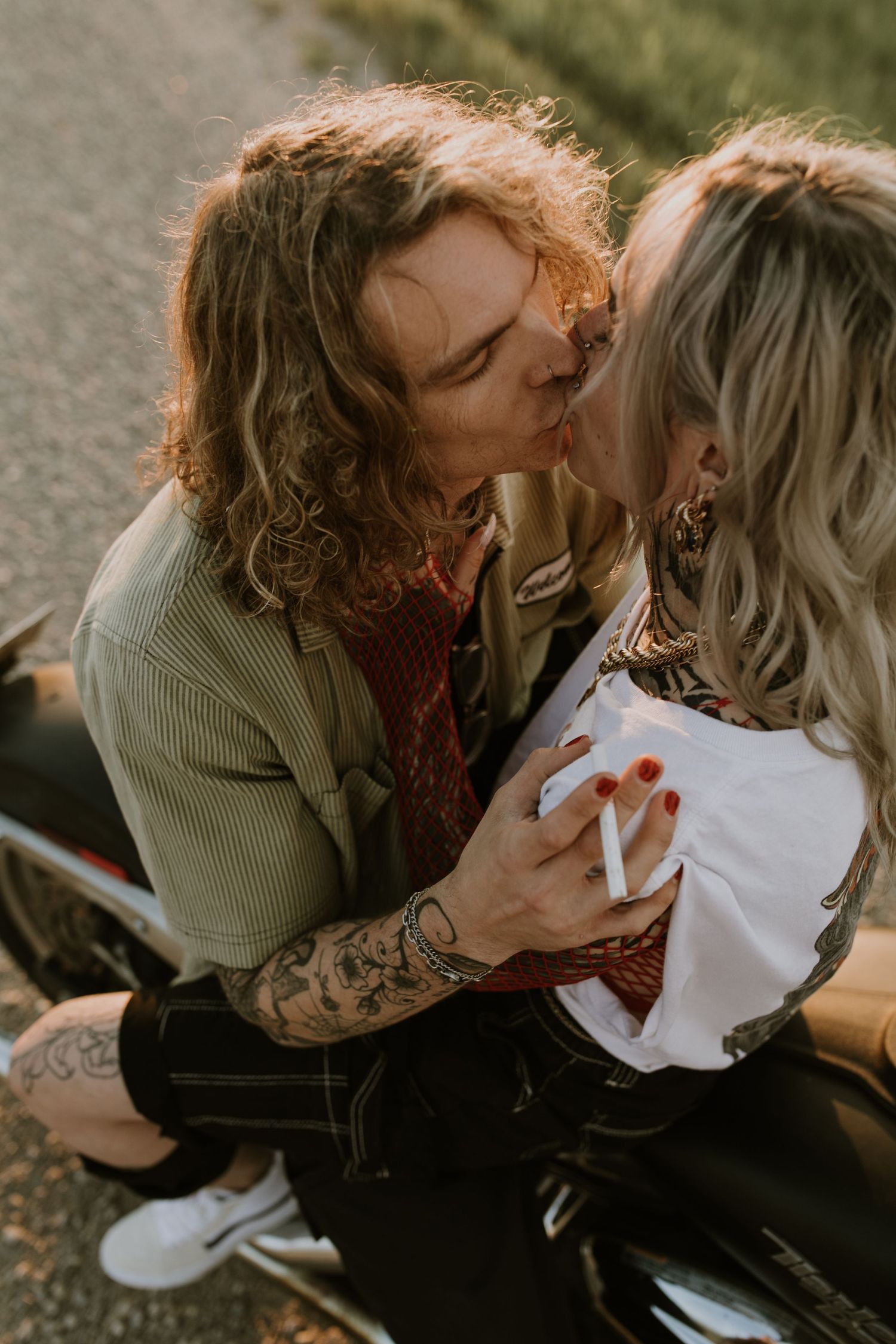 Romantic couple sharing intimate moment on motorcycle during sunset.