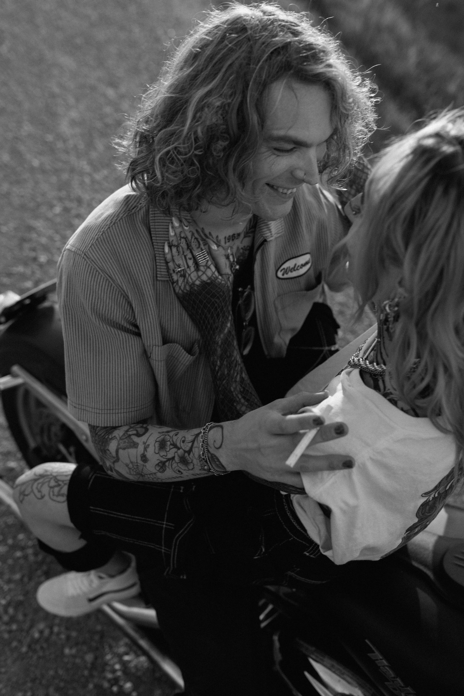 A candid moment captured in black and white showing two people sharing a laugh outdoors.