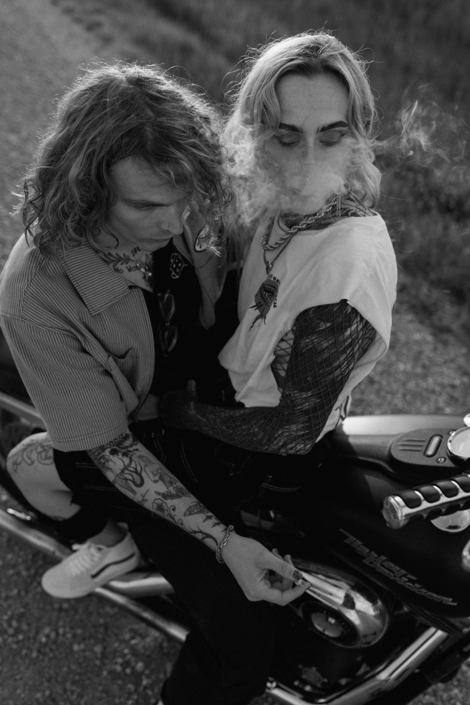 Artistic black and white photo of two people sitting on a motorcycle with smoke in the air.