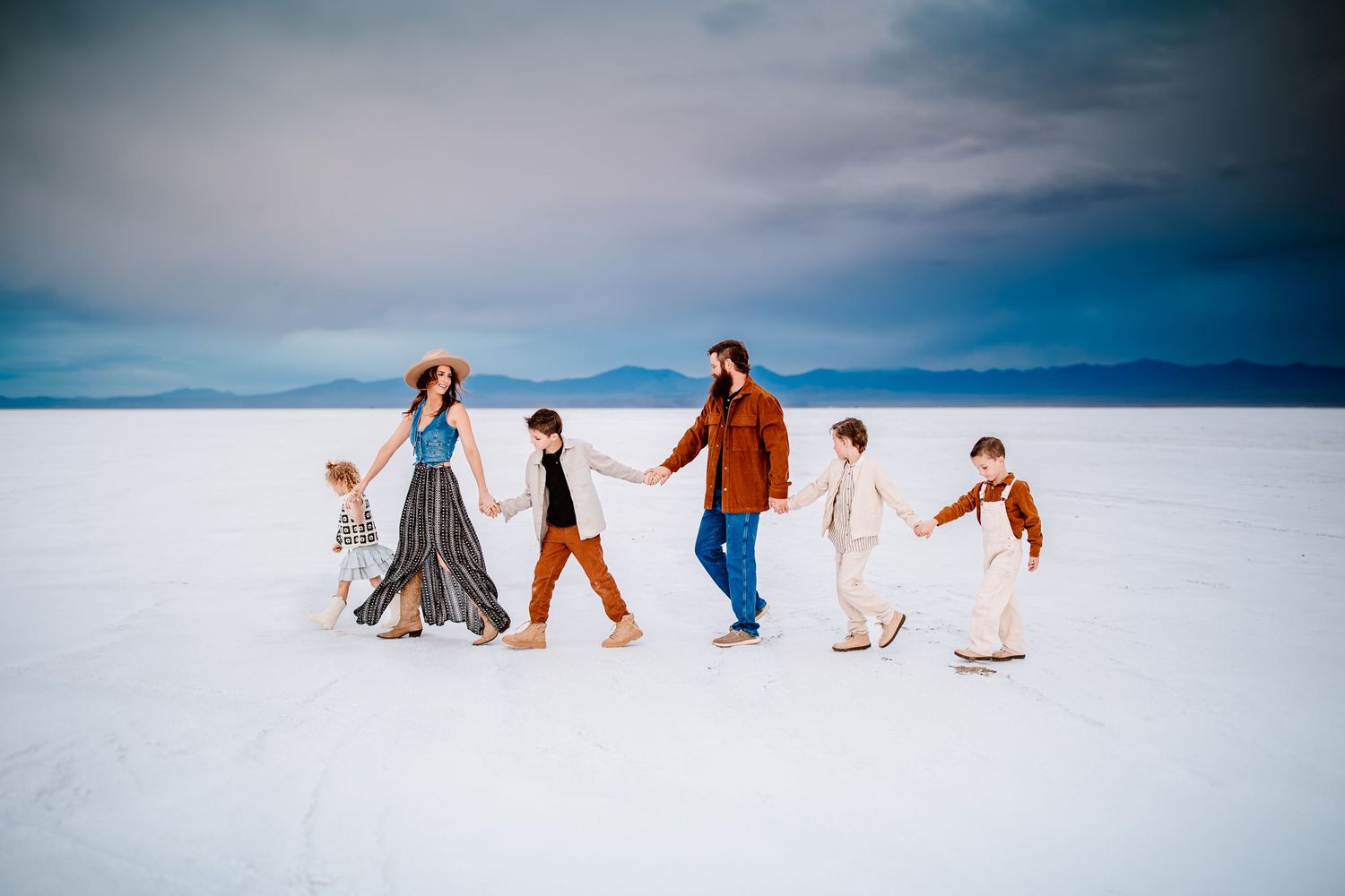 Family walking together across a stark white landscape under dramatic cloudy skies.