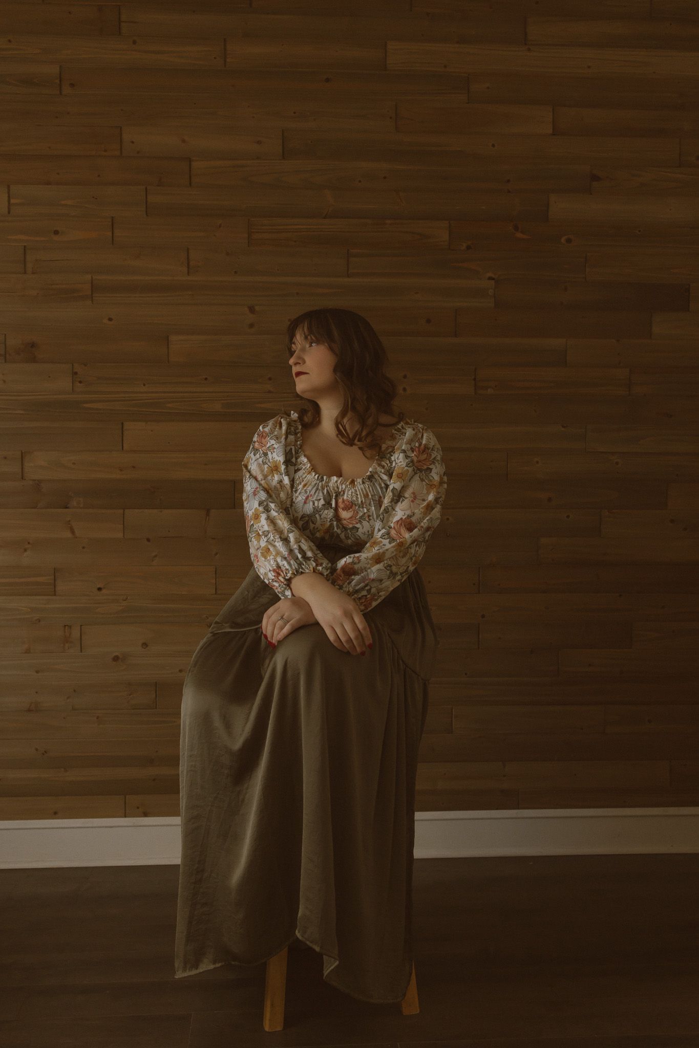 Cottage-core fashion portrait featuring an olive dress against wooden wall backdrop.