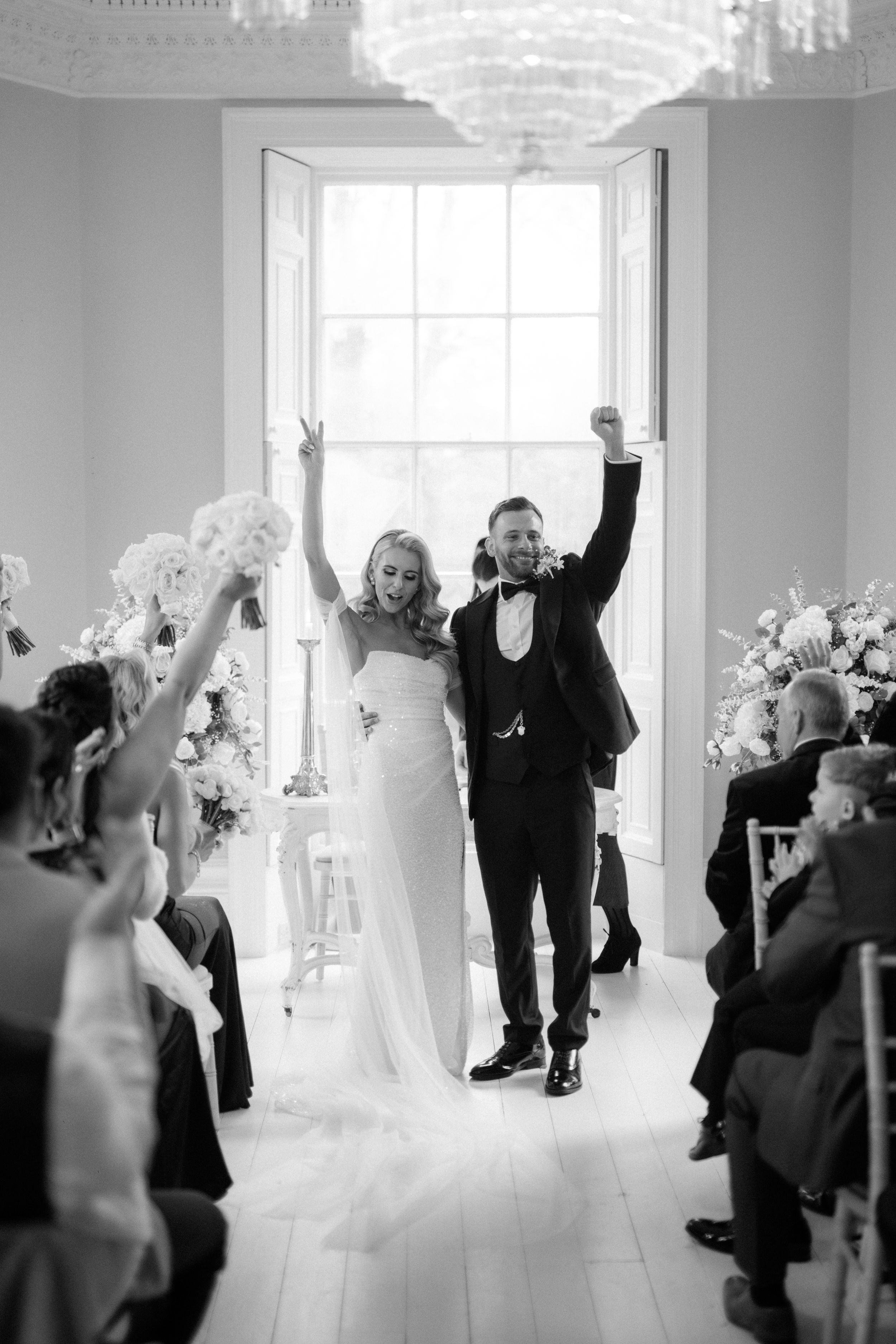 A joyful wedding ceremony moment with raised arms in celebration inside The Grand Lodge Oaklands, Beverly.