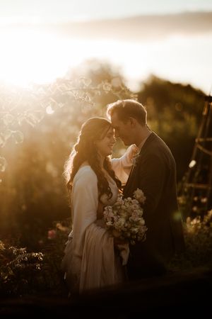 A romantic sunset portrait of a couple with a bouquet in golden light at Askham Hall.