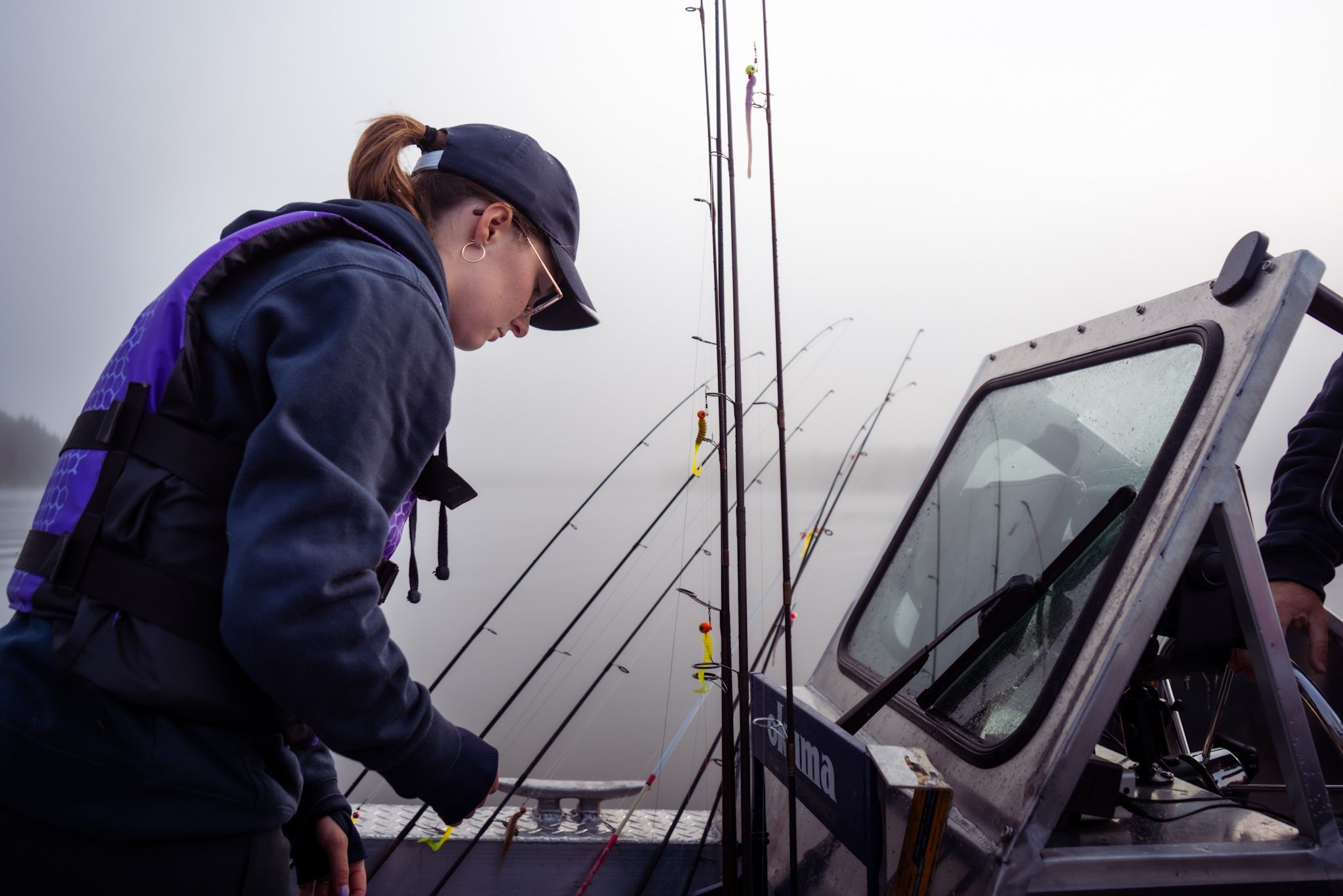 Person operating fishing equipment on a boat in misty conditions.