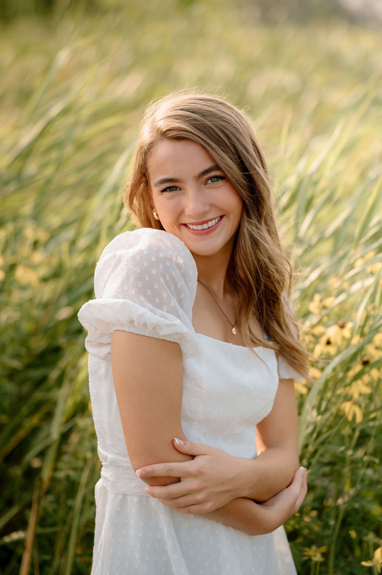 A joyful outdoor portrait featuring someone in a white dress surrounded by golden grass.