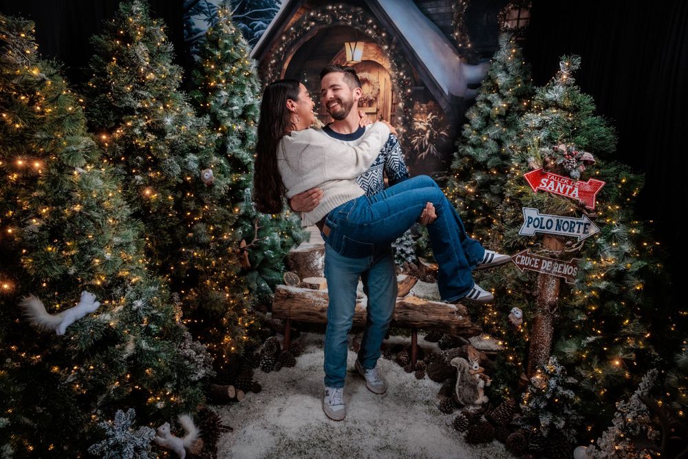 Festive holiday portrait session among decorated Christmas trees and twinkling fairy lights.